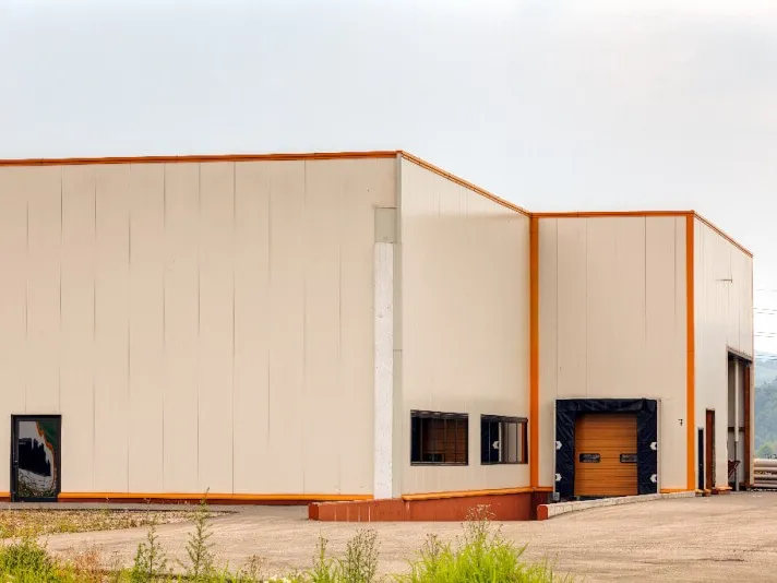 Beige steel commercial building with orange trim and a loading door
