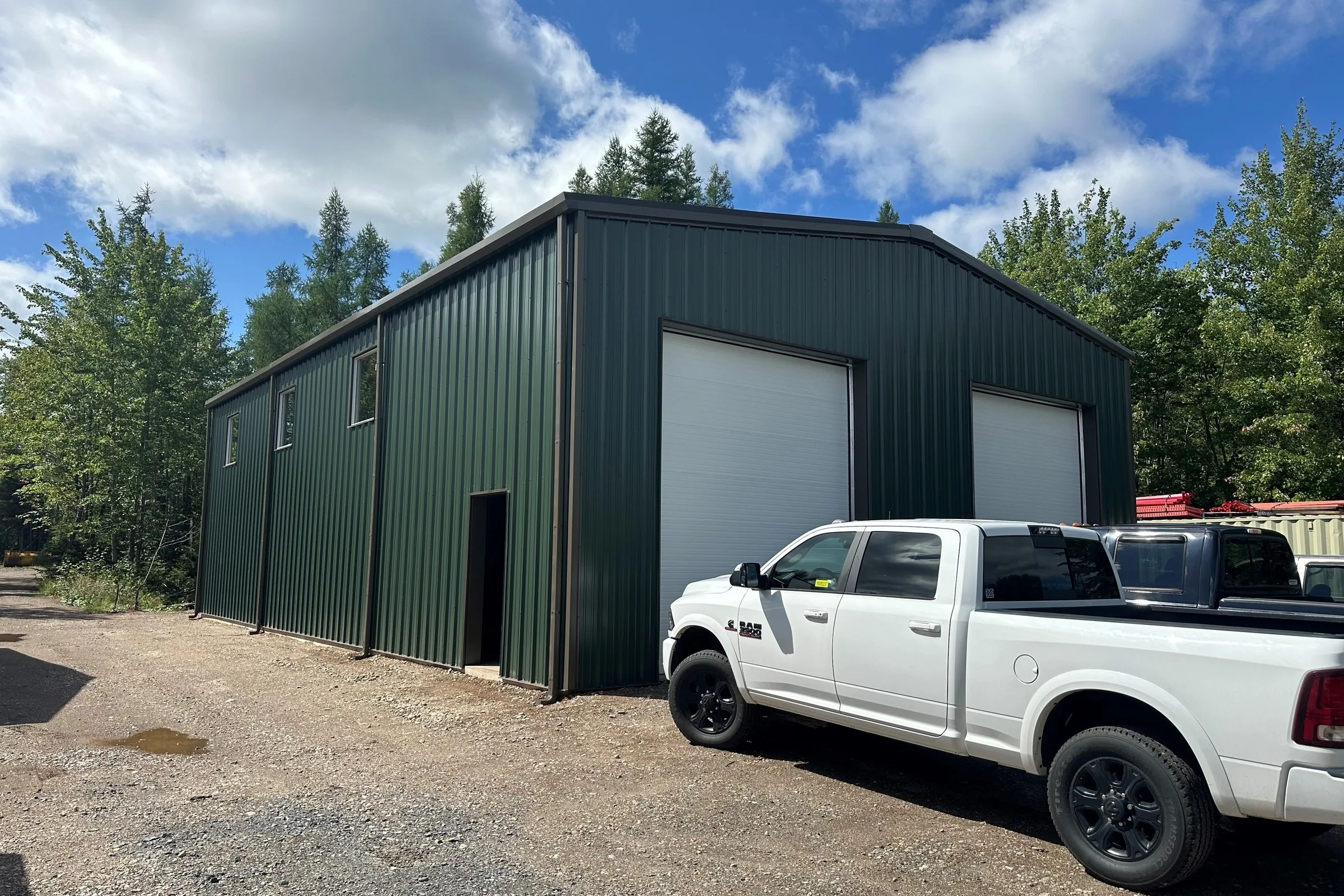 Green steel shop building with a pickup truck parked outside
