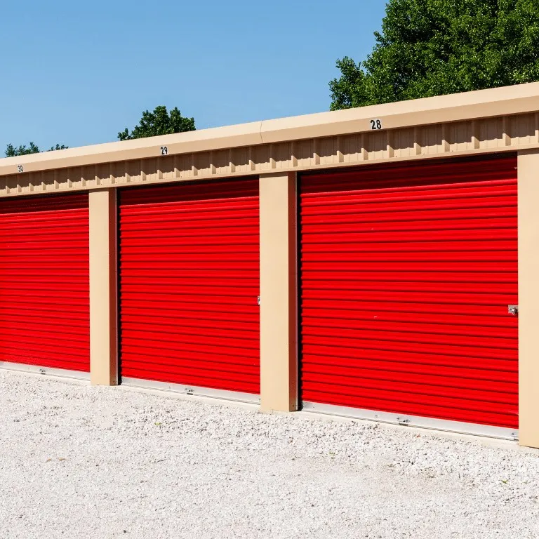 Row of red roll-up doors on a steel self-storage building