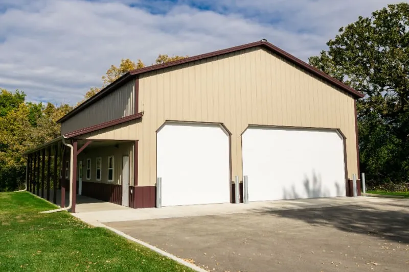 Tan steel building with two overhead doors and a covered porch